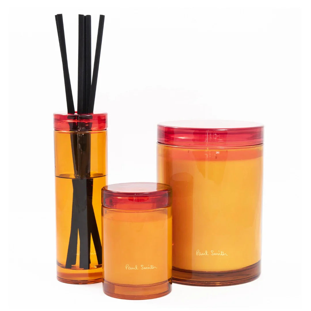 Drei zylindrische Behälter in verschiedenen Größen mit einem warmen, orange-roten Farbton. Der "Bookworm Diffuser" von "Paul Smith".