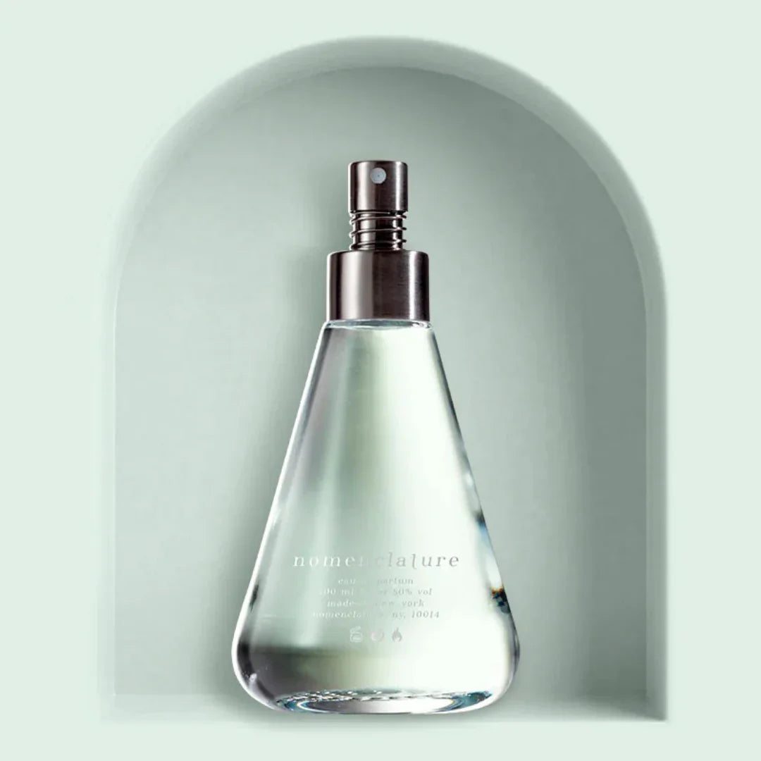 Klare Glasflasche mit Sprühkopf, spitz zulaufend, "nomenclature" Aufdruck. Produkt: shi_so, Anbieter: nomenclature.