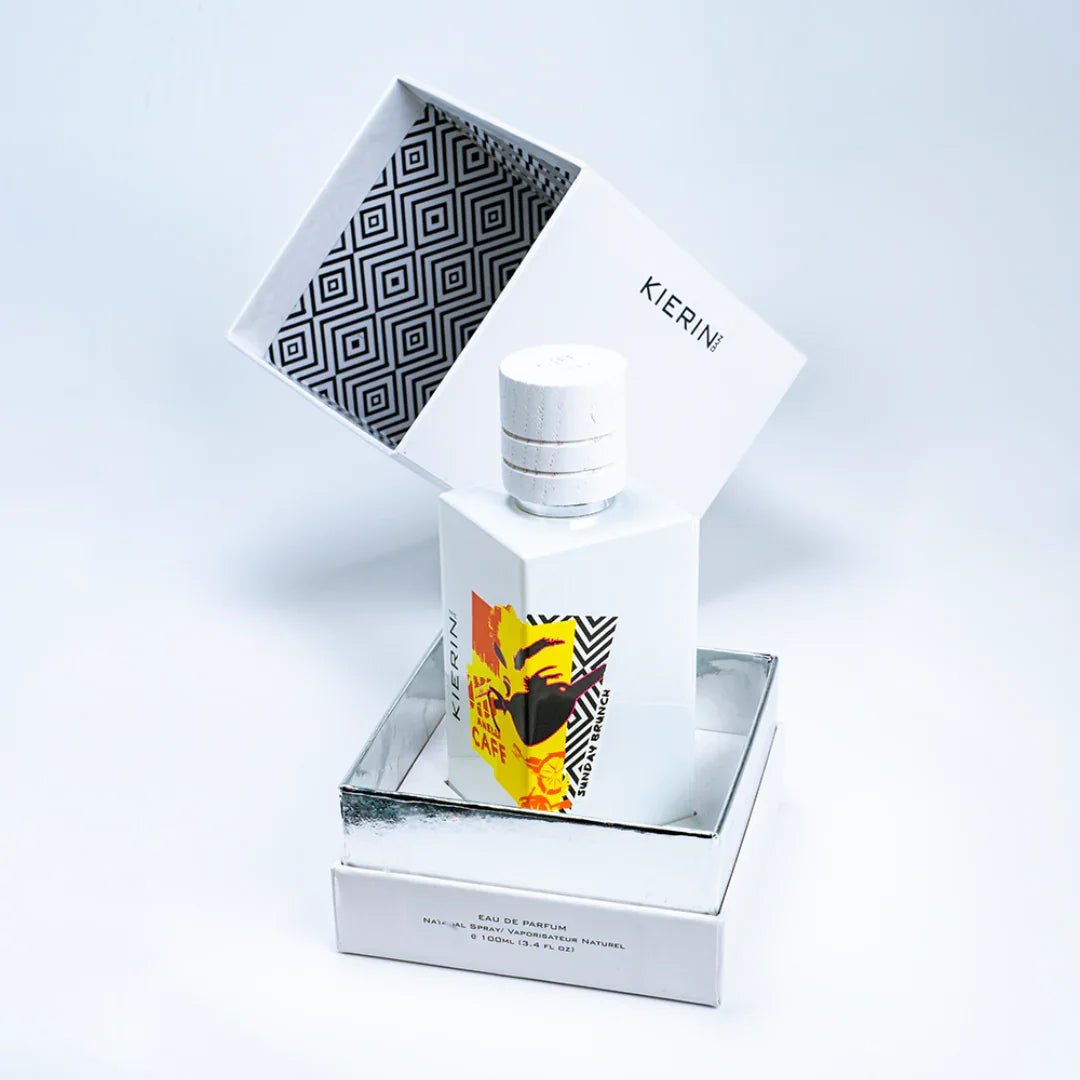 Parfümflasche "Sunday Brunch" von "Kierin NYC" in einem weißen, geometrisch gemusterten Karton. Die Flasche ist weiß mit gelbem Etikett.