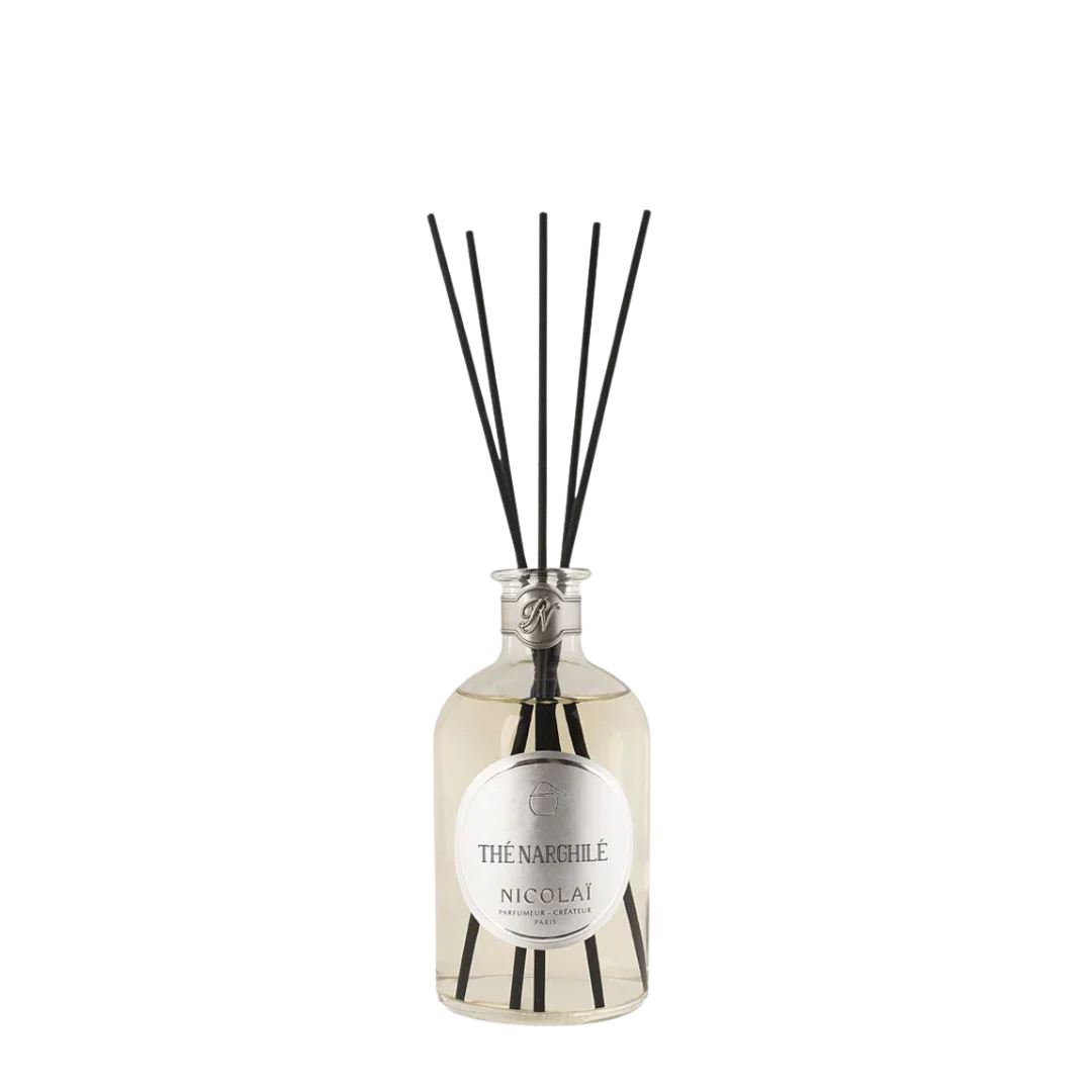 Glasflasche mit durchsichtigem Duftinhalt und schwarzem Verschluss, mehrere schwarze Diffuser-Stäbe darin. Produkt: Thé Narghilé - Diffuser, Hersteller: Nicolaï.