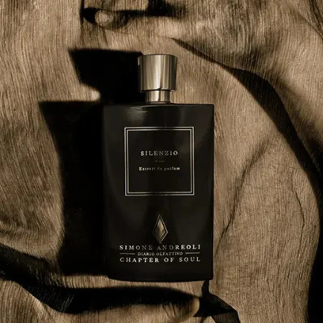 Schwarze Parfümflasche mit rechteckiger Form, silbernem Verschluss und der Aufschrift "Silenzio" von Simone Andreoli.