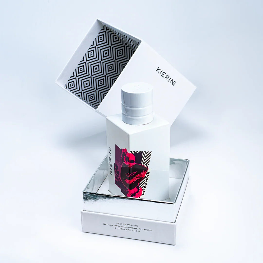Flakon des Parfüms "Nitro Noir" von Kierin NYC. Der weiße Flakon hat ein geometrisches Muster im Deckel und ein farbiges Etikett.