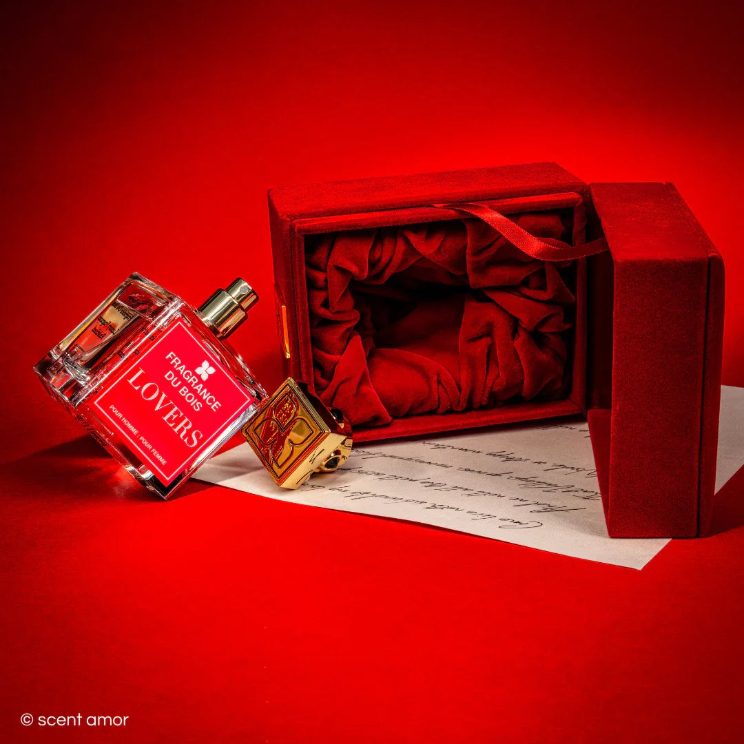 Parfümflasche "Lovers" von FRAGRANCE DU BOIS, mit rotem Etui und goldener Kappe, auf einem Schriftstück platziert.