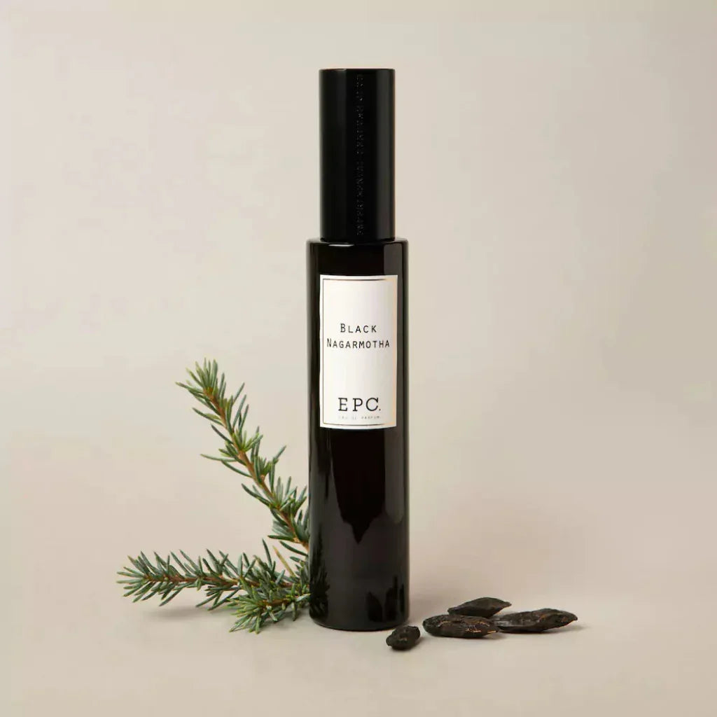 Schwarze Flasche mit schwarzem Verschluss, Etikett mit "Black Nagarmotha" und "EPC". Daneben liegen Zweig und Samen. Titel: Black Nagarmotha, Anbieter: Experimental Perfume Club.