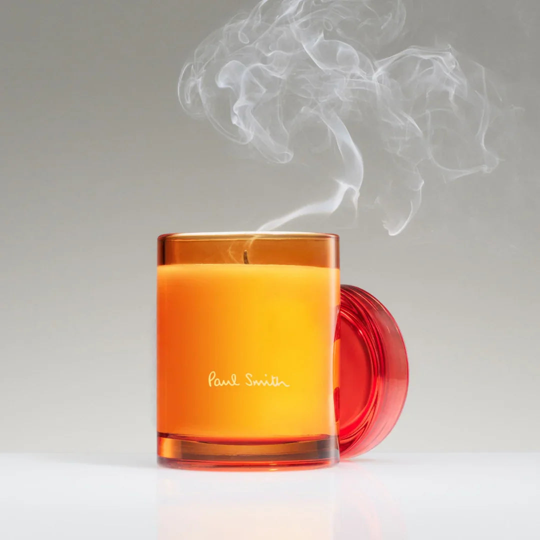 "Bookworm Duftkerze" von Paul Smith. Orangefarbene Glasduftkerze mit abnehmbarem farblich abgestimmtem Deckel.