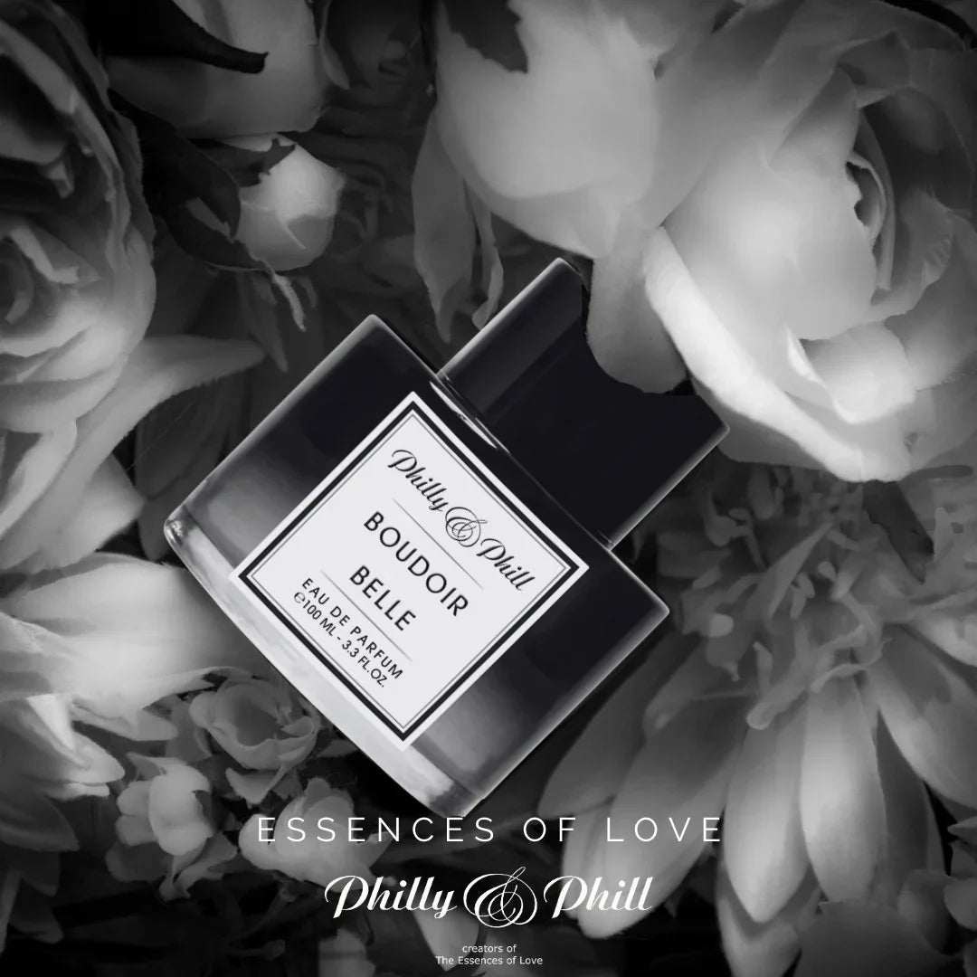Schwarz-weißer Flakon des Eau de Parfum "BOUDOIR BELLE" von Philly & Phill, umgeben von Blumen.
