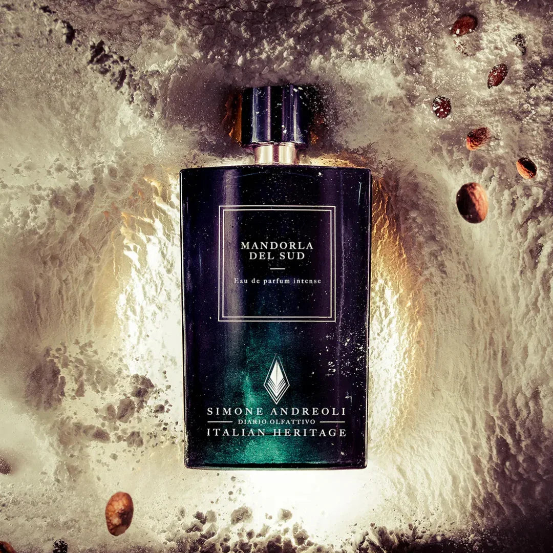 Dunkelblaues Parfümflakon "Mandorla del Sud" von Simone Andreoli mit goldenen Akzenten, umgeben von Mandelstücken.
