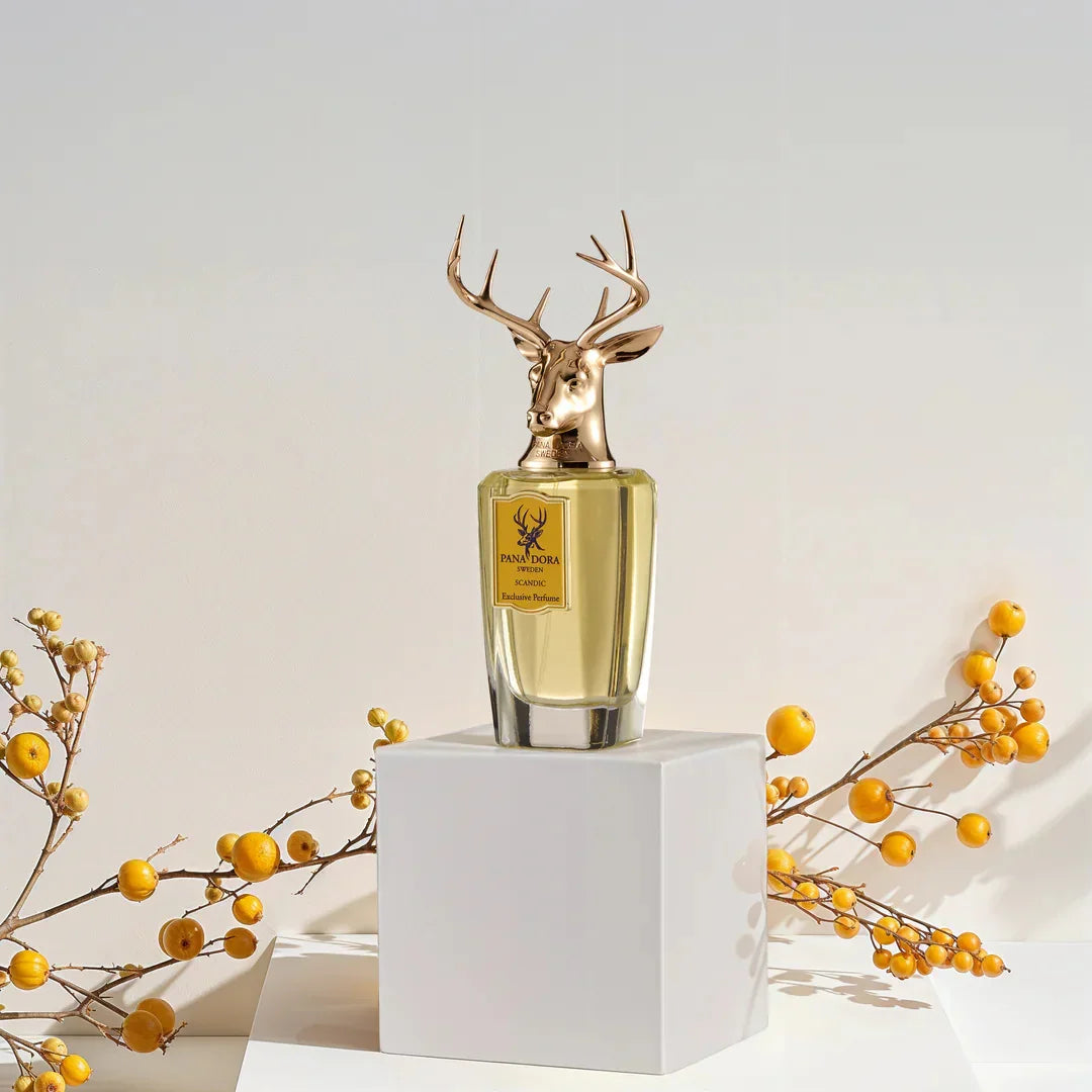 Parfümflasche "Scandic" von Pana Dora, goldene Hirschkopf-Verschlusskappe, transparentes Glas mit gelblicher Flüssigkeit.