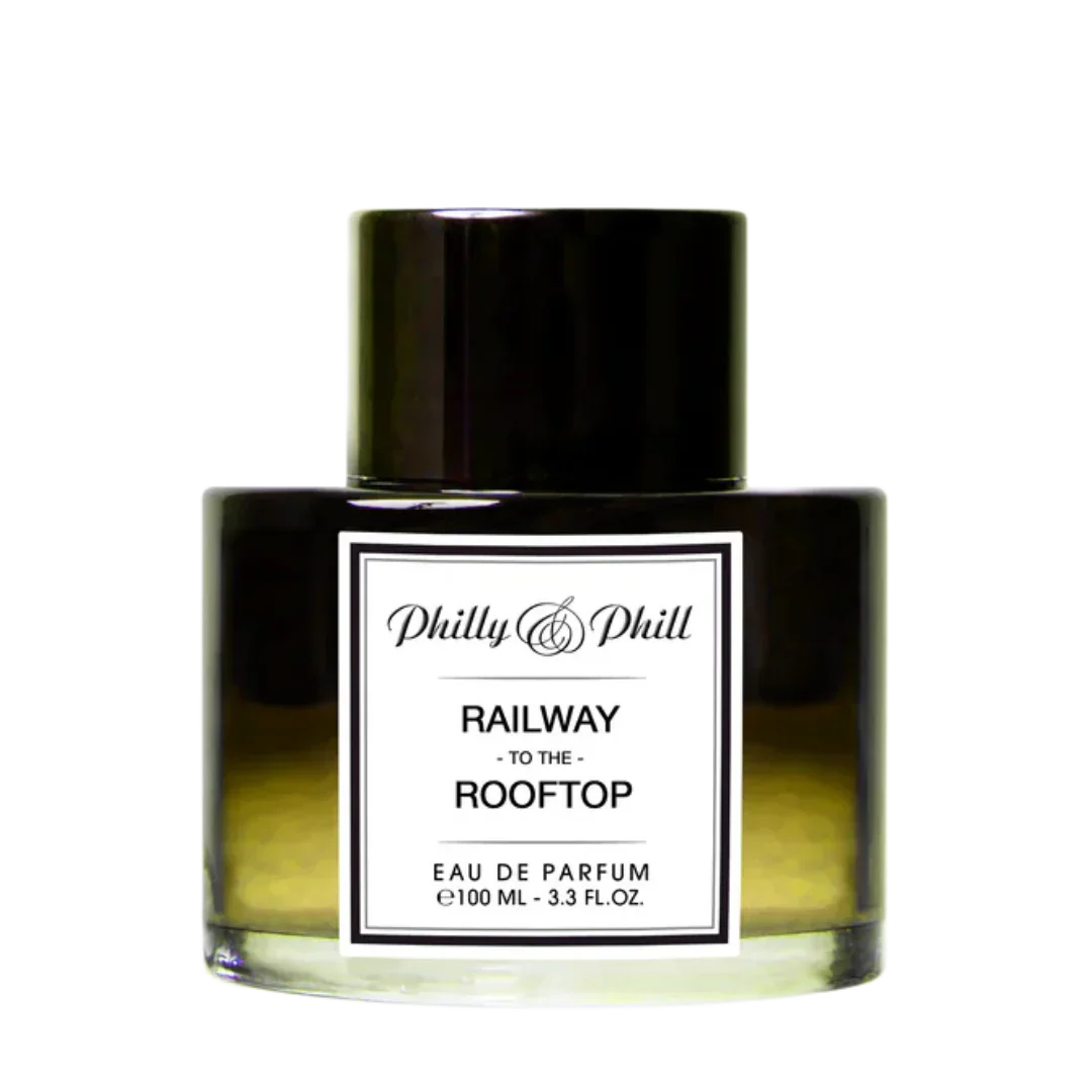 Das Bild zeigt ein Parfümflakon mit schwarzem Verschluss. Auf dem Etikett steht "RAILWAY TO THE ROOFTOP" von Philly & Phill.