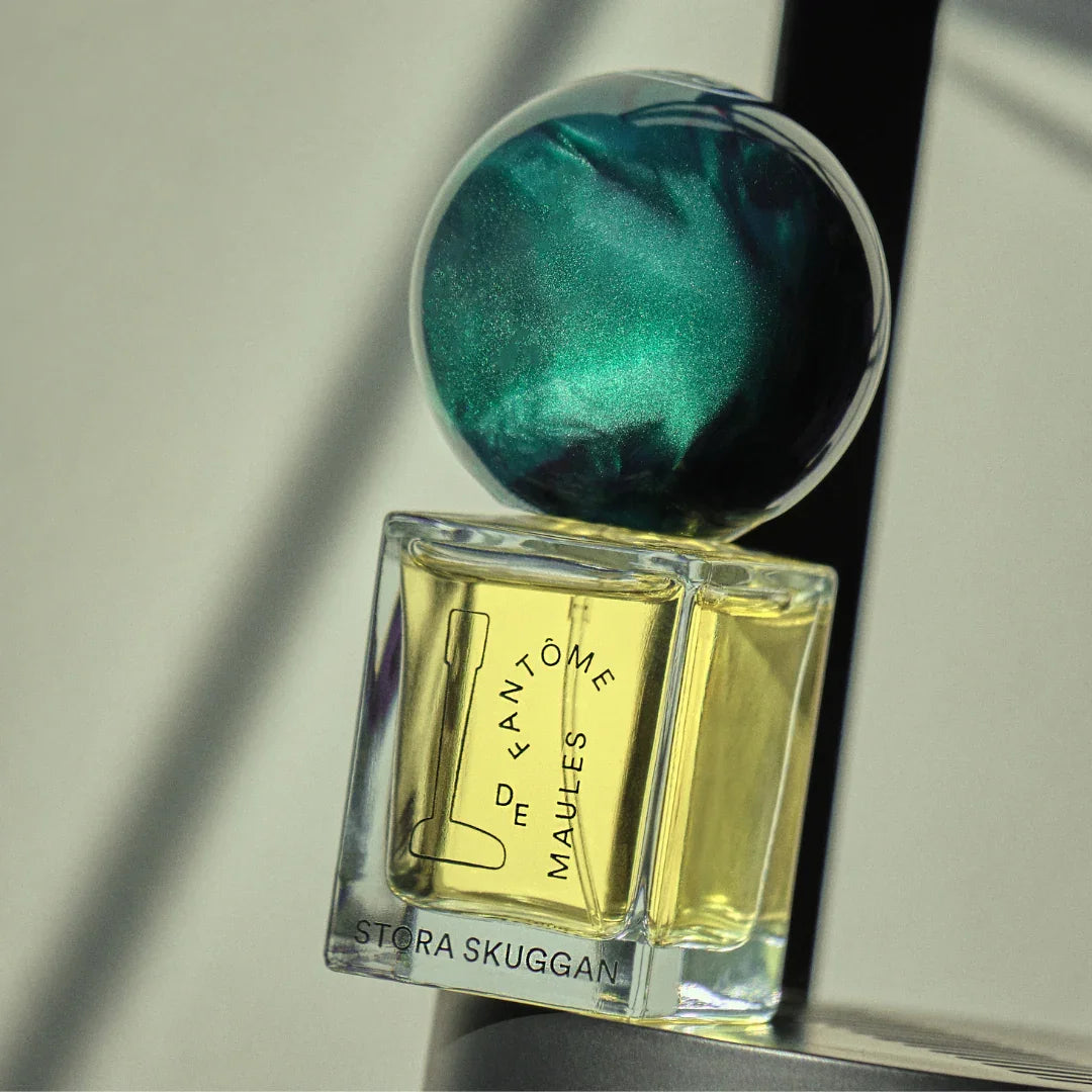 Parfümflakon "Fantôme de Maules" von Stora Skuggan, mit würfelförmigem Glasflakon und schimmerndem, rundem Deckel.