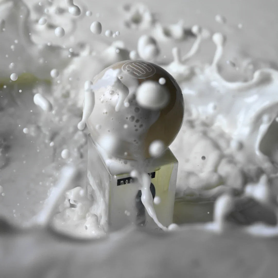 Flasche "Moonmilk" von Stora Skuggan, gekrönt von einer beige Kugel, umgeben von spritzender Milch.