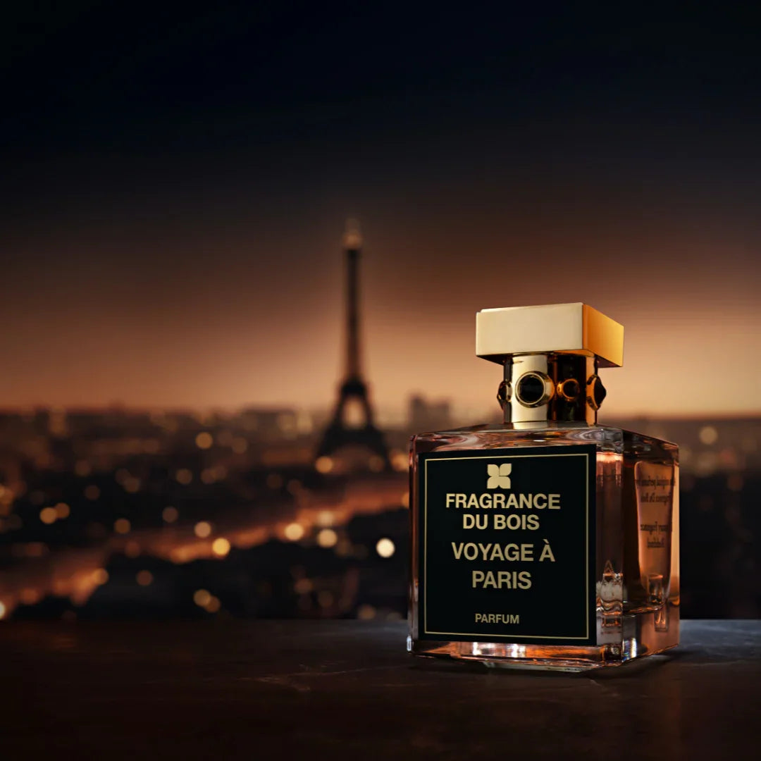 Parfümflasche "Voyage à Paris" von FRAGRANCE DU BOIS mit goldfarbenem Verschluss, Paris-Skyline im Hintergrund.