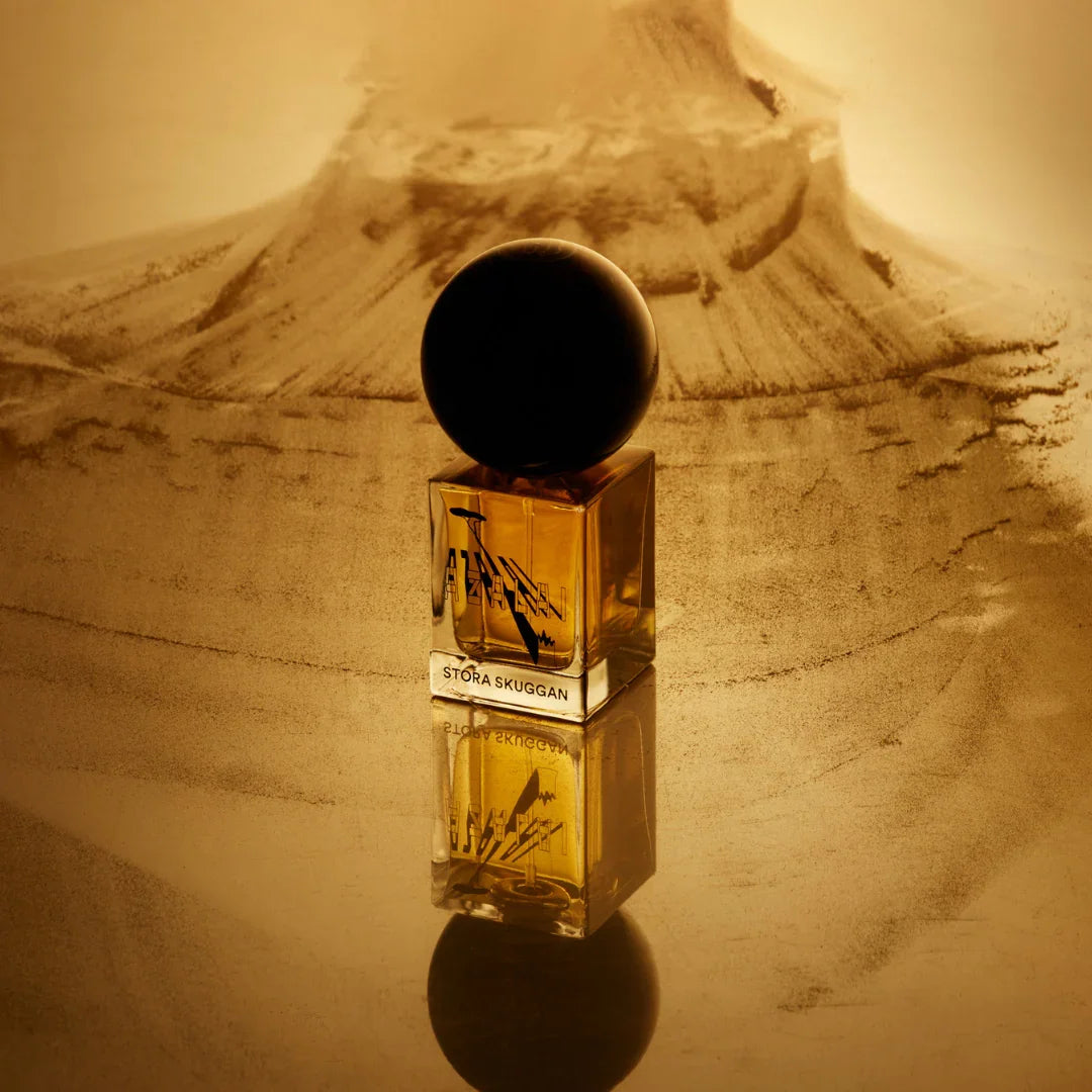 Flakon des "Azalai" Parfums von Stora Skuggan mit schwarzem runden Verschluss, reflektiert auf einer glatten Oberfläche.