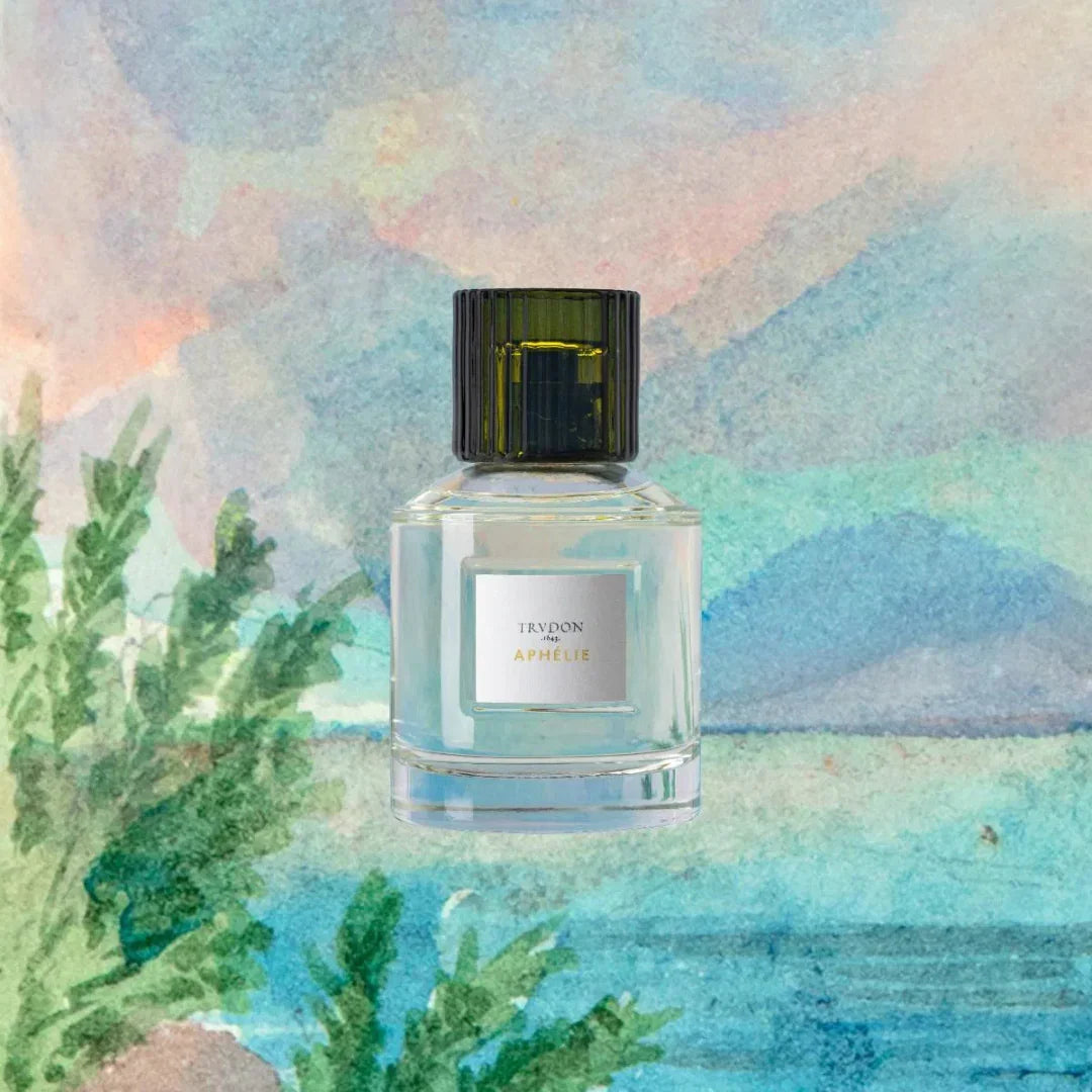 Glasflakon des Parfums "APHÉLIE" von Trudon mit schwarzem Verschluss, vor Aquarellhintergrund mit Pflanzenmotiv.
