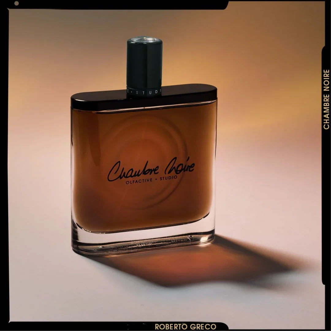 Parfümflakon "Chambre Noir" von Olfactive Studio, rechteckig, mit dunklem Verschluss und bernsteinfarbenem Inhalt.