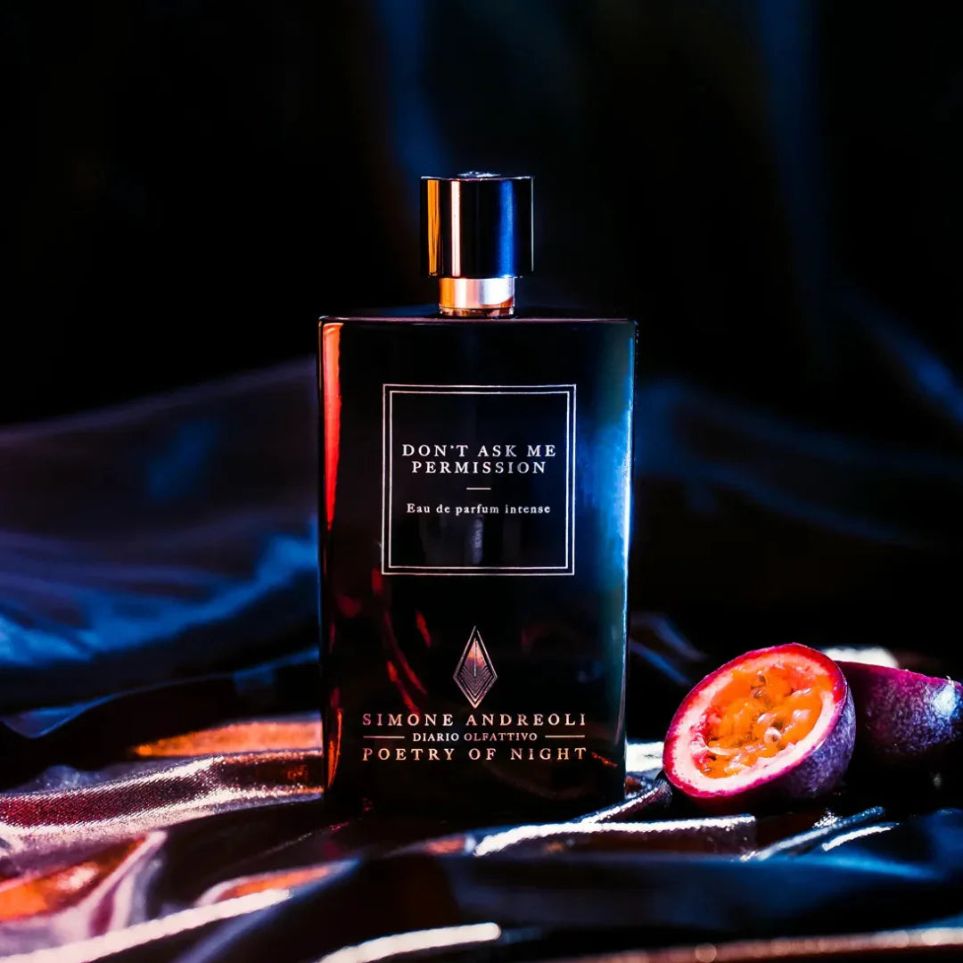 Schwarzer Flakon des Parfums "Don´t Ask me Permission" von "Simone Andreoli" mit Metallverschluss, daneben aufgeschnittene Passionsfrucht.