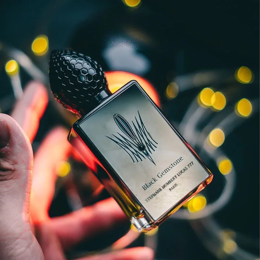 Ein Parfümflakon mit schwarzer Verschlusskappe und goldener Flüssigkeit. Produkt: Taklamakan von Stéphane Humbert Lucas.