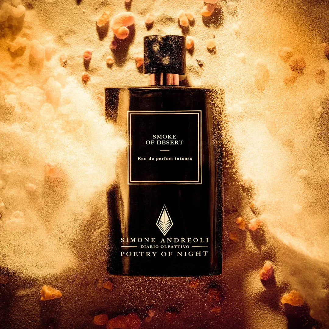 Parfumflasche "Smoke of Desert" von Simone Andreoli, schwarz mit weißer Aufschrift, umgeben von Sand und kleinen Steinen.