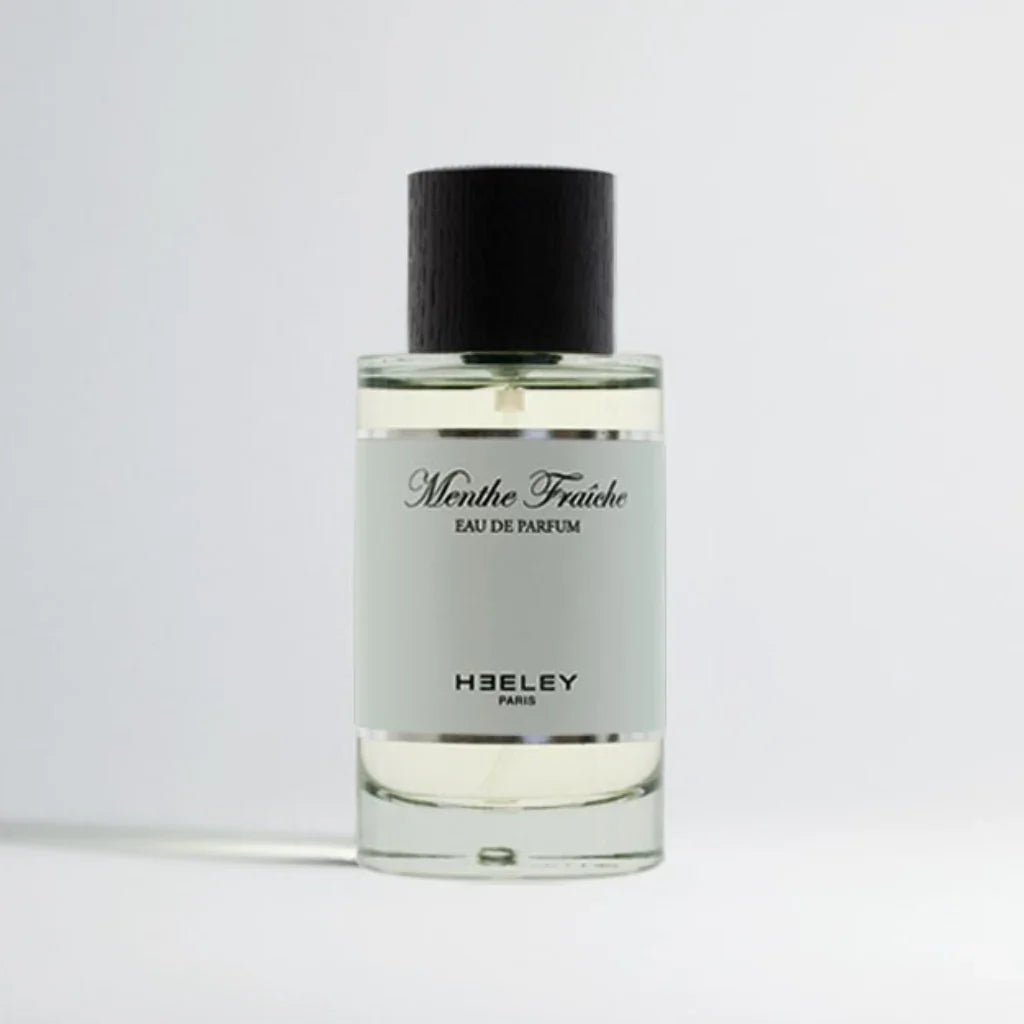 Transparente Parfümflasche "Menthe Fraîche" von Heeley mit schwarzem Deckel und weißem Etikett.