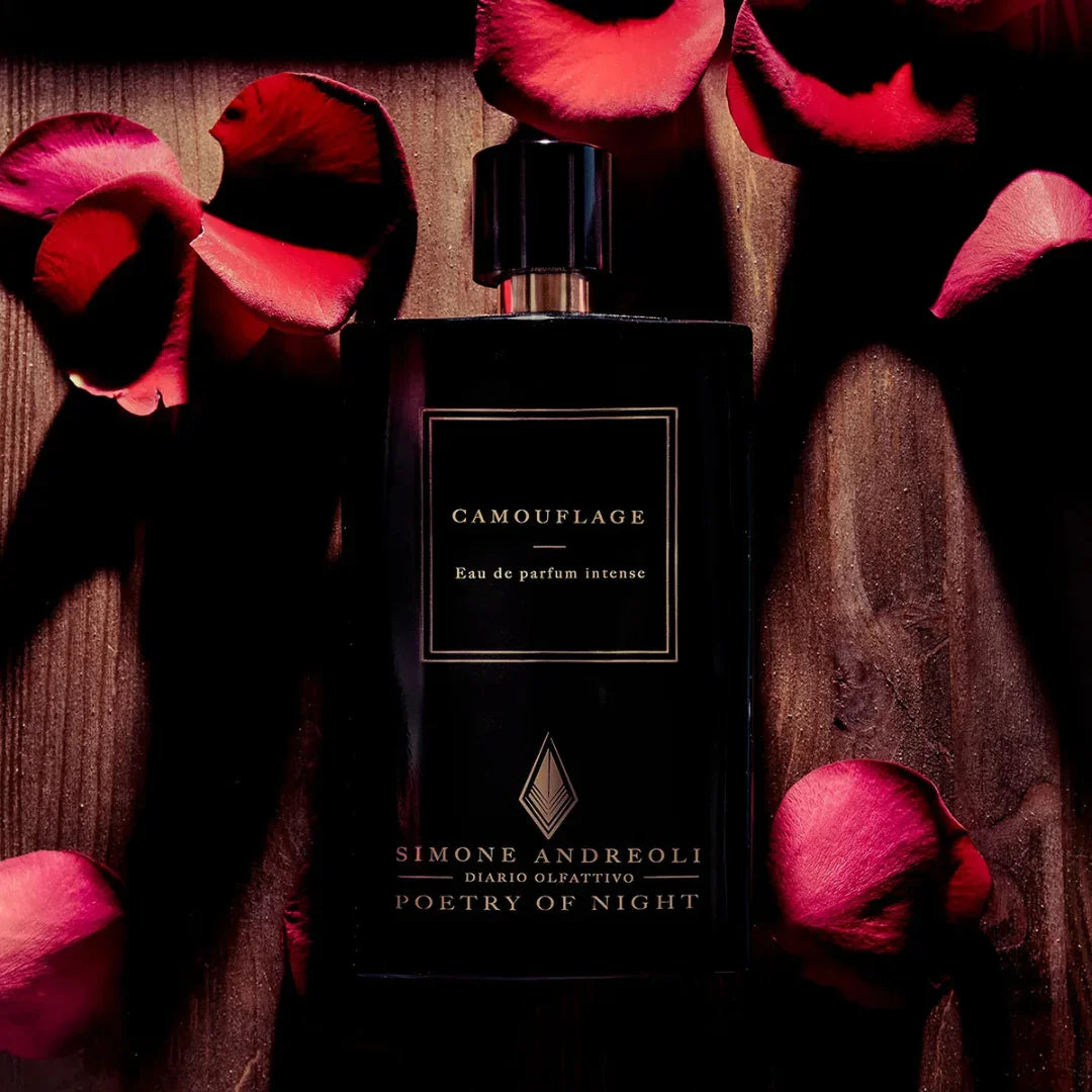 Flakon des Parfums "Camouflage" von Simone Andreoli, umgeben von roten Rosenblütenblättern.