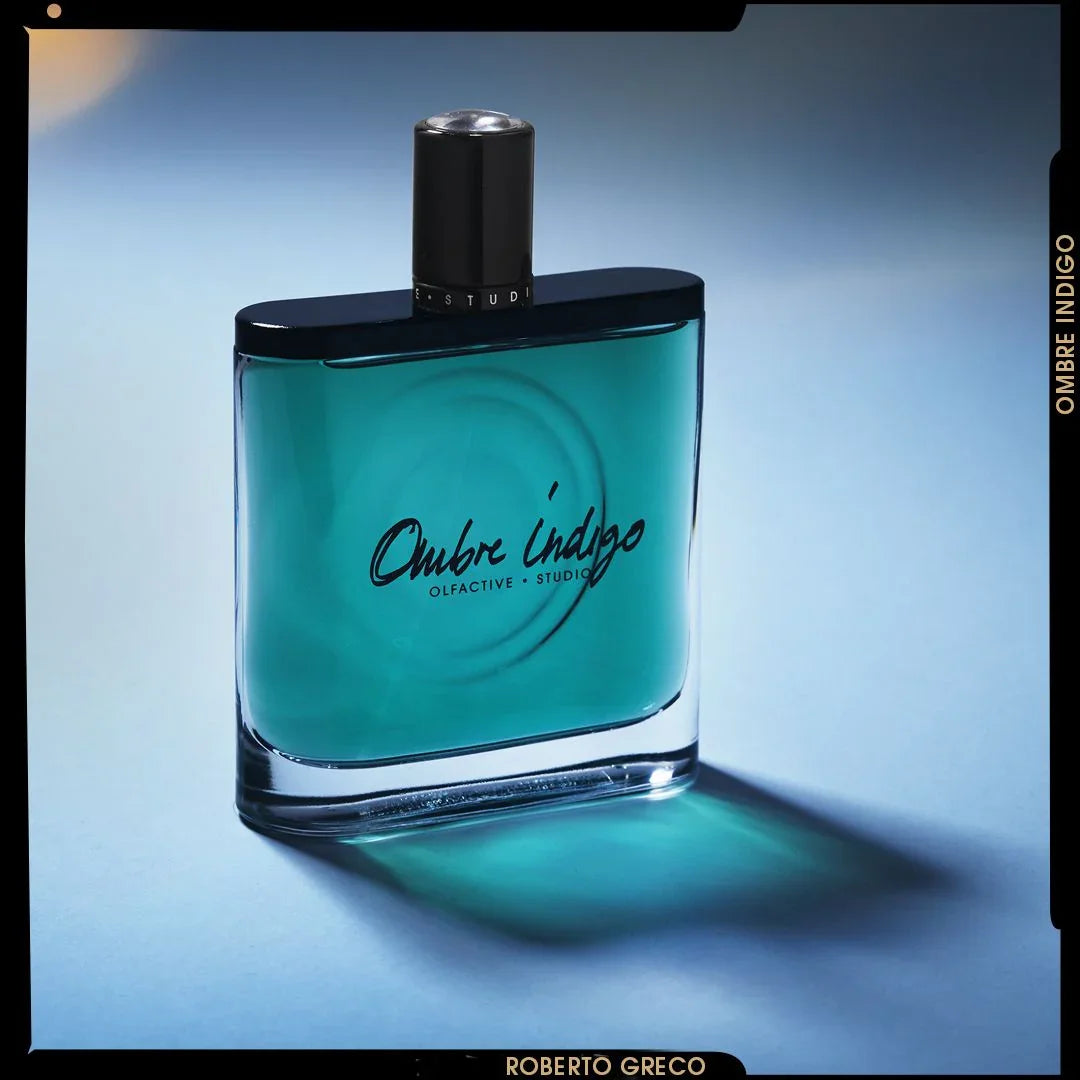 Parfümflakon "Ombre Indigo" von Olfactive Studio, rechteckig mit schwarzem Verschluss und türkisfarbener Flüssigkeit.