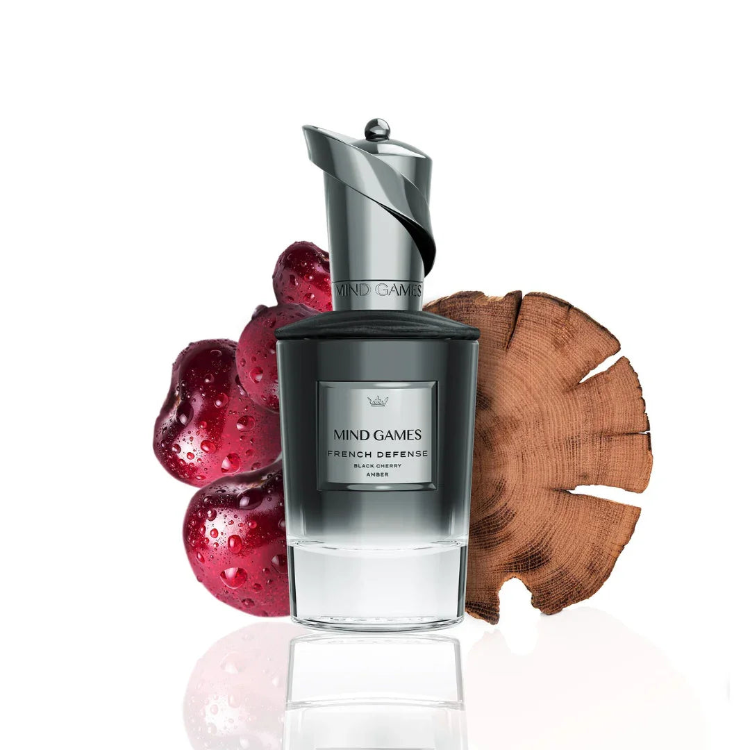 Parfümflakon "French Defense" von Mind Games, mit glänzendem silbernen Verschluss, umgeben von Früchten und Holz.