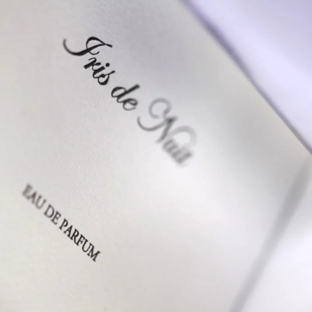 Nahaufnahme des Textes "Iris de Nuit Eau de Parfum" von Heeley auf weißem Hintergrund.