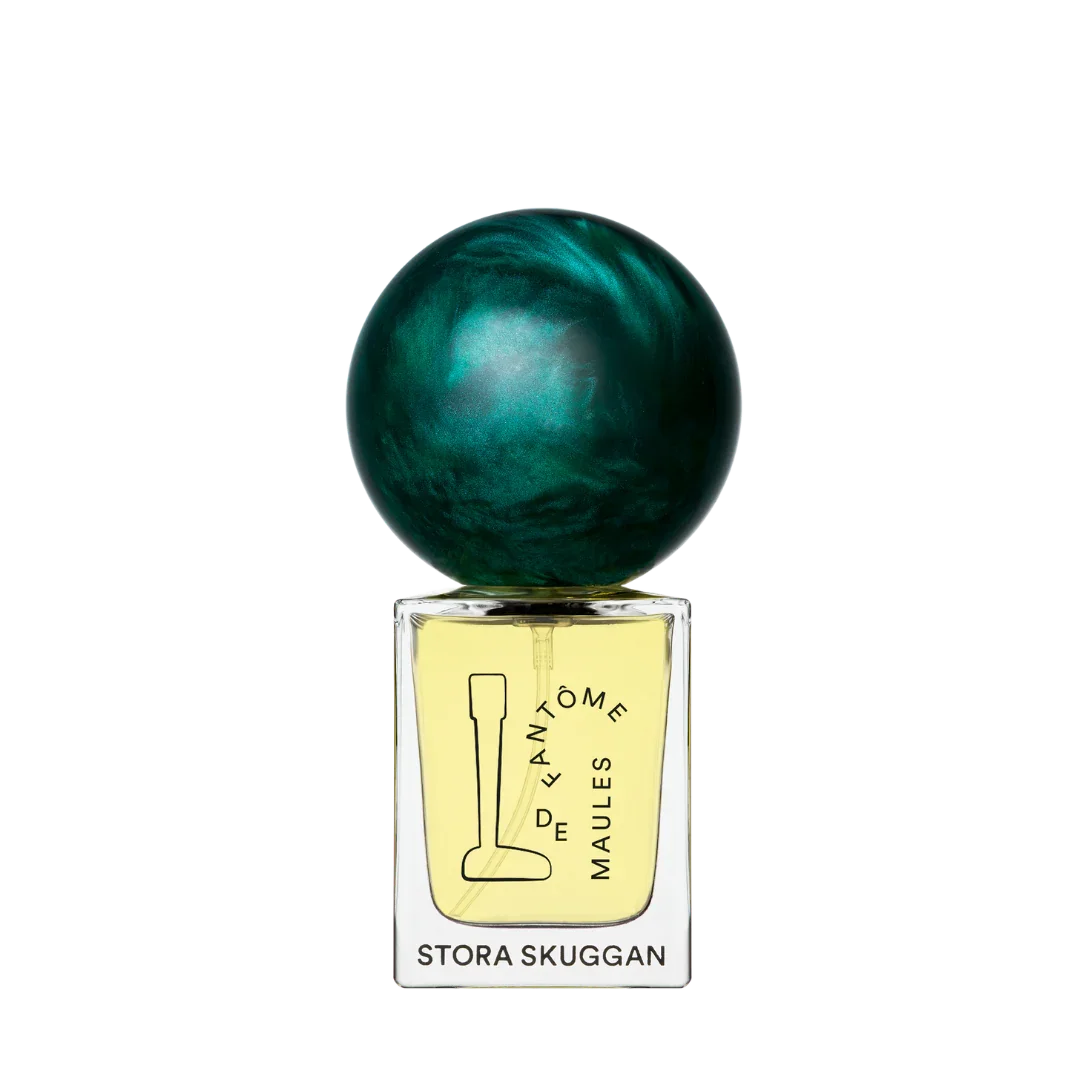 Das Produkt "Fantôme de Maules" von Stora Skuggan zeigt ein Parfümfläschchen mit einer gelben Flüssigkeit und einem auffälligen, kugelförmigen, grün-schimmernden Verschluss.