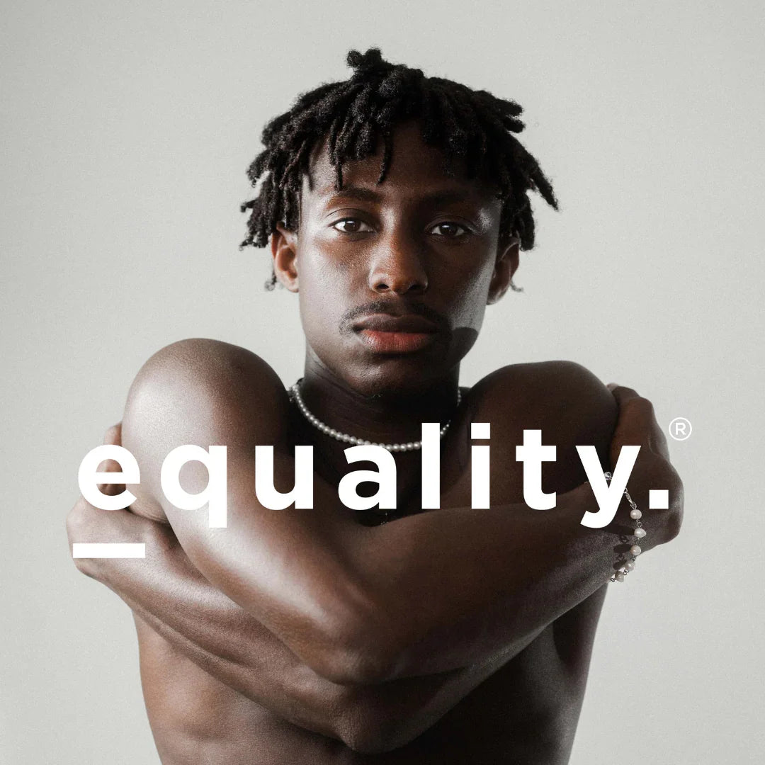 Oberkörperfreier Mann mit Perlenketten und -armband, die Arme vor der Brust verschränkt. Text "equality." auf dem Bild.