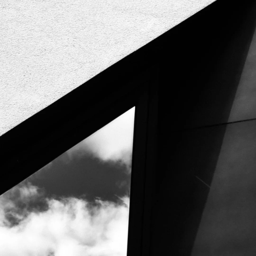 Das Bild zeigt "Cuir Dandy" von FUMparFUM. Moderne Architektur in Schwarz-Weiß mit Wolkenreflexionen im Glas.