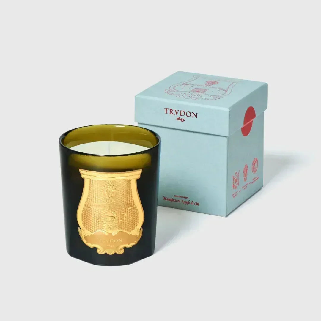 Duftkerze "SPIRITUS SANCTI" von Trudon in einem dunkelgrünen Glas mit goldenem Wappen, neben einer blauen Schachtel.