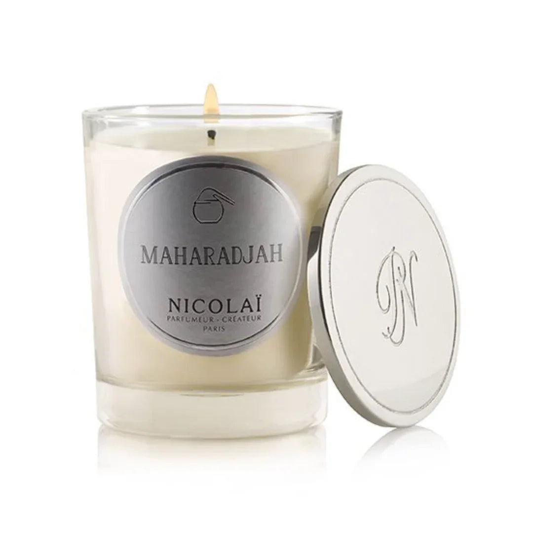 Weiße Duftkerze in einem klaren Glas mit einem silbernen Etikett "Maharadjah - Nicolaï" und einem abnehmbaren Deckel.