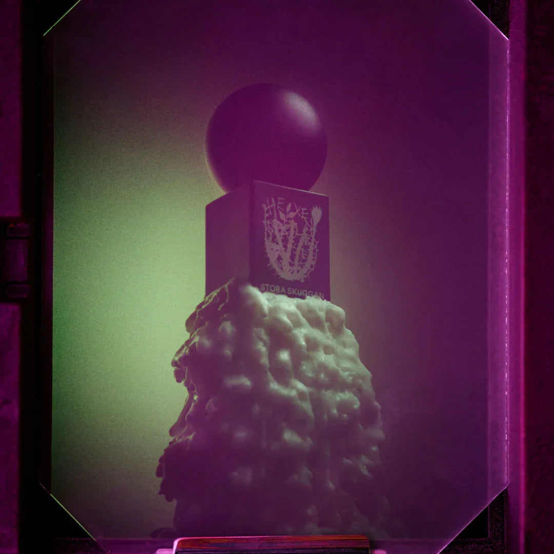 Produkt "Hexensalbe" von Stora Skuggan: Ein dunkler Flakon mit rundem Verschluss, auf einem mit Schaum bedeckten Sockel.