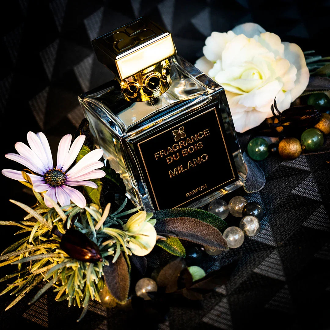 FRAGRANCE DU BOIS Milano Duftflakon mit goldener Kappe, von Blumen und Steinen umgeben.
