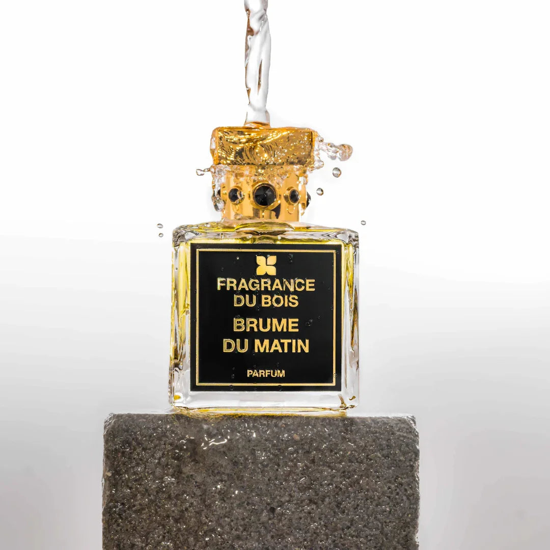 Rechteckiger Parfümflakon "Brume du Matin" mit goldener Kappe von FRAGRANCE DU BOIS, Wasser fließt darüber.