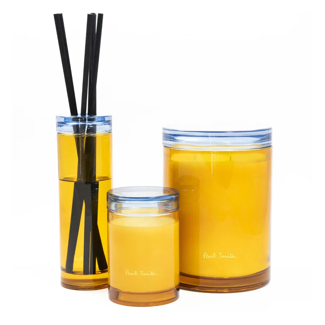 Drei transparente Glasbehälter mit gelber Flüssigkeit, beschriftet mit "Paul Smith". Enthält Duftstäbchen. Titel: Day Dreamer Diffuser. Anbieter: Paul Smith.