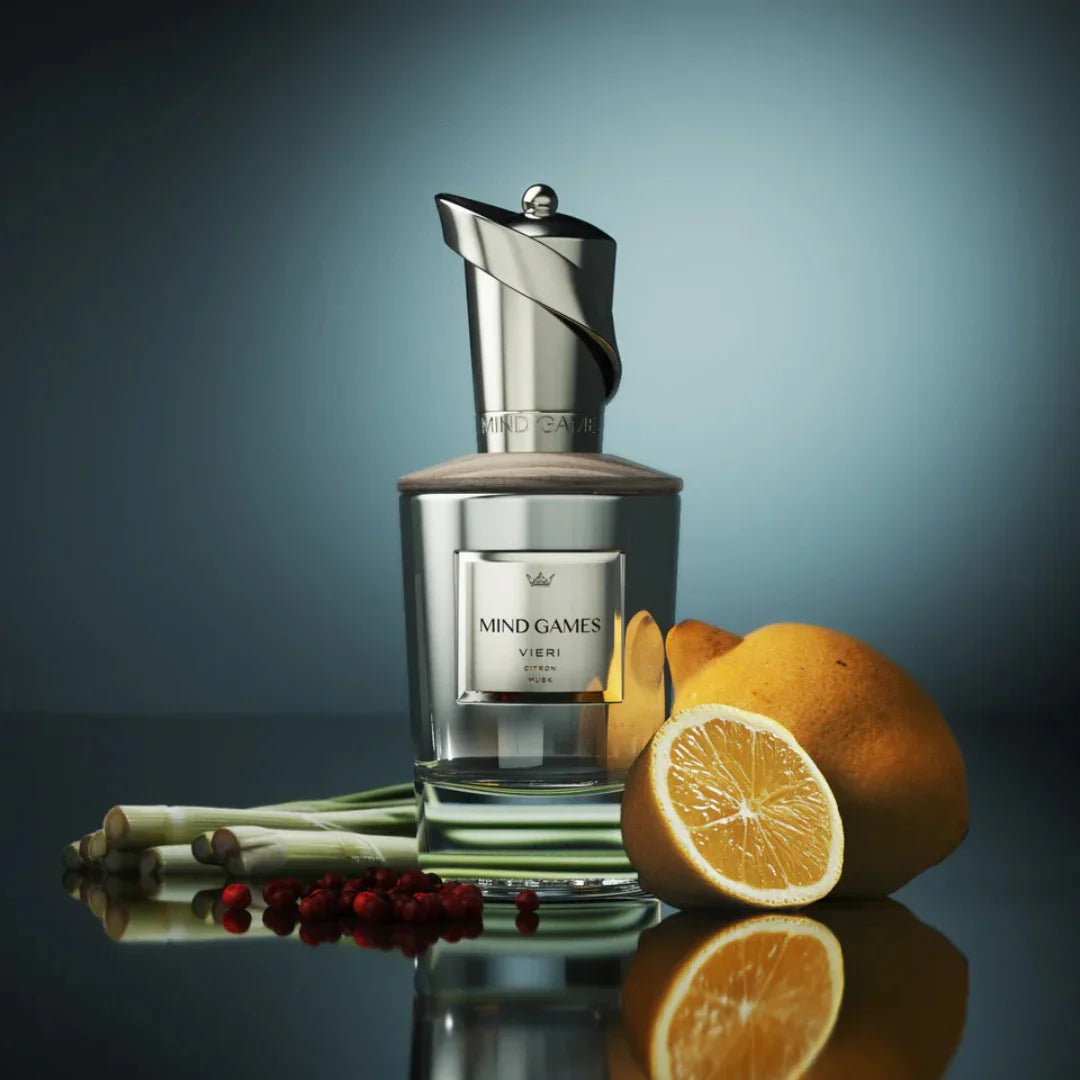 Parfumflakon mit silberner Kappe und Etikett "Mind Games Vieri" von Mind Games, umgeben von Zitrusfrüchten und Gewürzen.