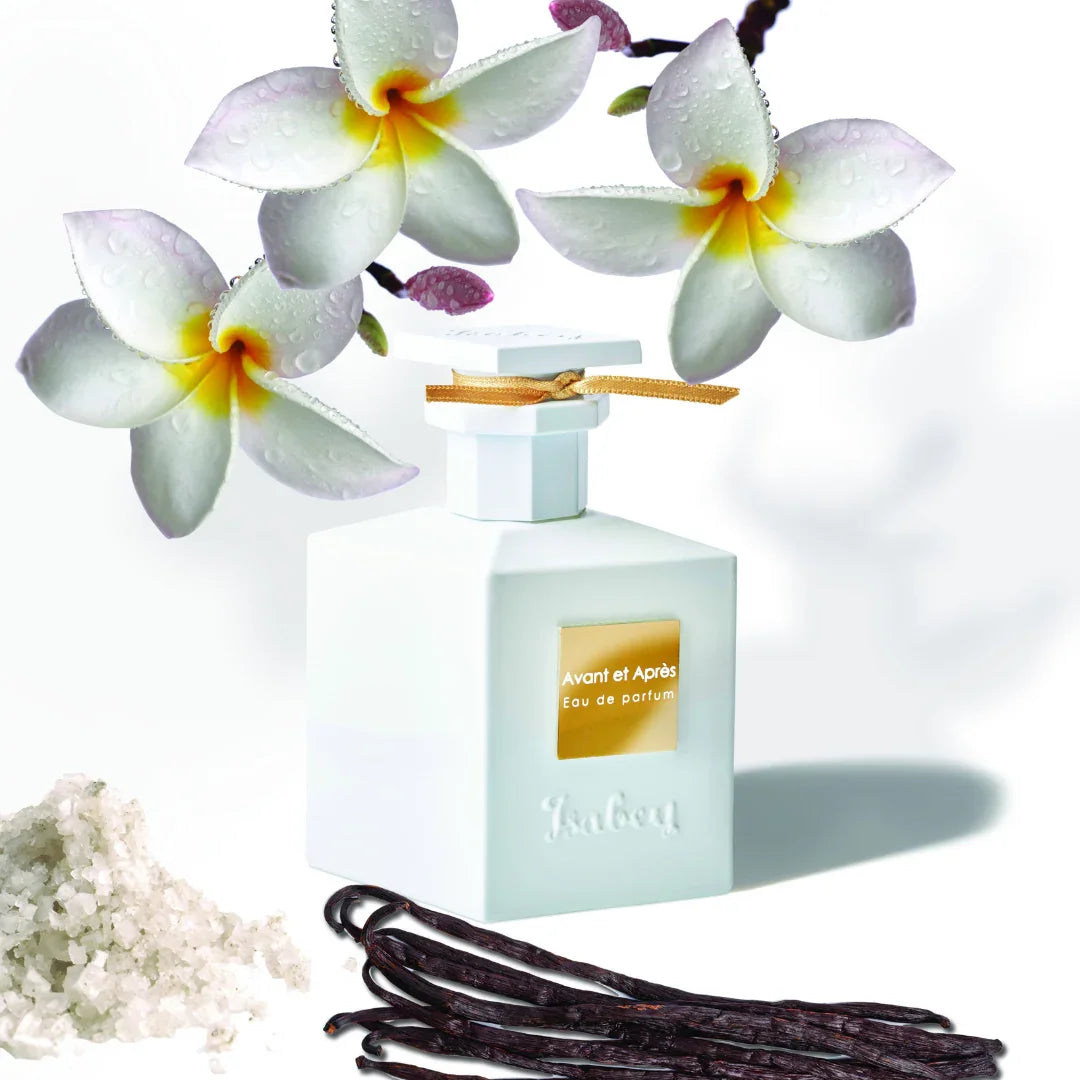 Weiße Parfümflasche mit goldener Aufschrift "Avant et Après Eau de parfum", umgeben von weißen Blüten und Vanilleschoten, Hersteller Isabey.