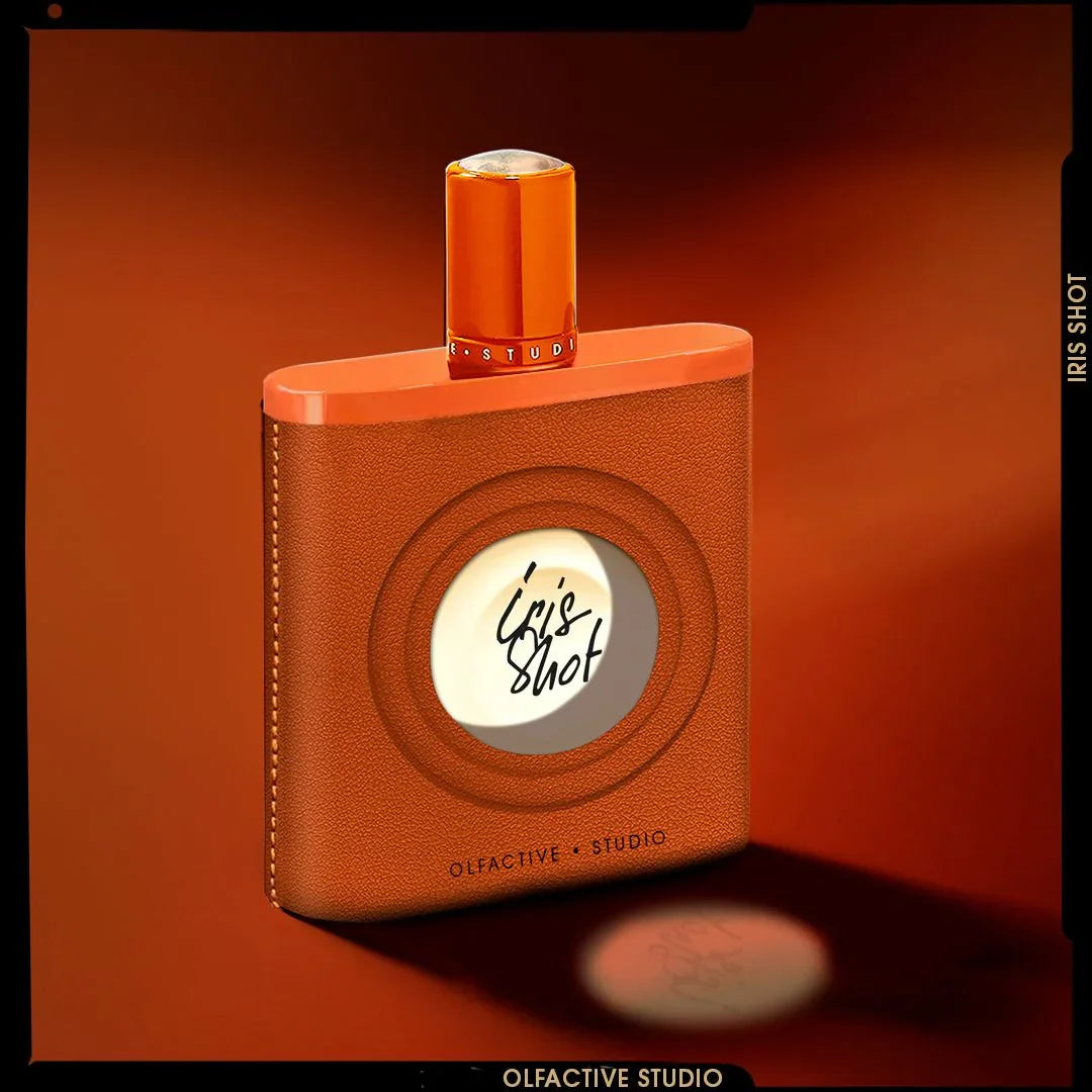 Braunes rechteckiges Parfümfläschchen mit rundem Etikett "Iris Shot" vorne, von Olfactive Studio; orangefarbener Verschluss.