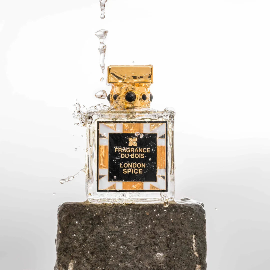 Das Produkt "London Spice" von "FRAGRANCE DU BOIS" ist eine Parfümflasche mit einem goldenen Verschluss und einem rechteckigen Etikett auf der Vorderseite. Die Flasche steht auf einem Stein und wird von spritzendem Wasser umgeben.