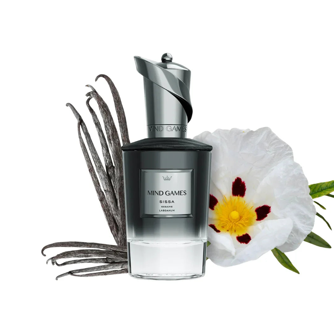Das Produkt "Sissa" von "Mind Games" zeigt ein elegantes Parfümfläschchen mit schwarzen Akzenten. Daneben sind Vanilleschoten und eine weiße Blume zu sehen.
