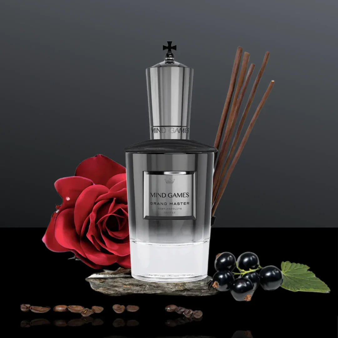 Parfümflasche „Grand Master“ von Mind Games, silbern und transparent mit schwarzem Deckel, umgeben von einer roten Rose, Beeren, Zimtstangen und Kaffeebohnen.