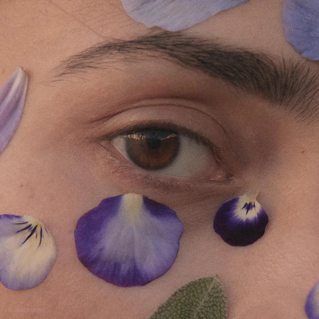Nahaufnahme eines Auges, umgeben von violetten und weißen Blütenblättern. Produkt: Of True Minds, Anbieter: Liis.