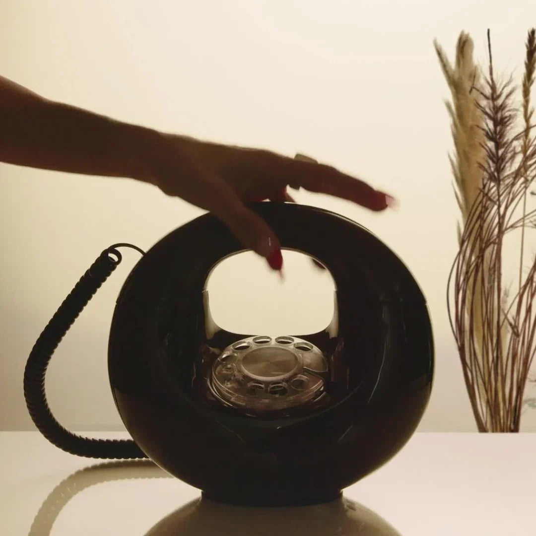 D.S. & Durga Brown Flowers, Parfümflasche in Form eines runden, schwarzen Telefons mit Wählscheibe und einer Hand, die daran greift.