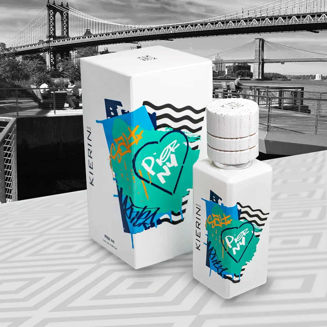 Das Produkt "Pier NY" von "Kierin NYC" zeigt eine weiße Parfümflasche mit farbigem Streetart-Design neben einer passenden Verpackung.