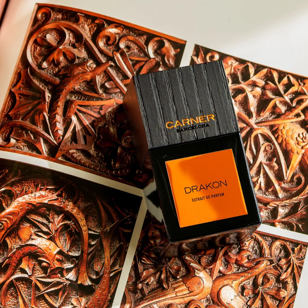 Parfümflasche "Drakon" von Carner Barcelona mit schwarzem, holzstrukturiertem Verschluss und orangem Etikett.