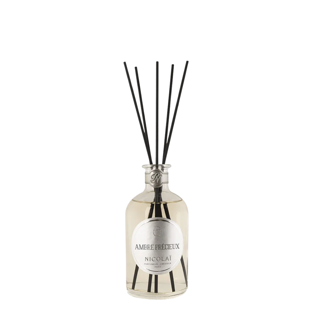 Glasflakon mit schwarzem Diffuserstäben, Etikett "Ambre Précieux - Nicolaï" auf der Vorderseite.