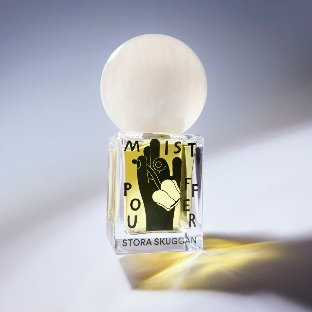 Flakon des Parfüms "Mistpouffer" von Stora Skuggan mit rundem, opaken Verschluss und grafischem Design auf der Flasche.