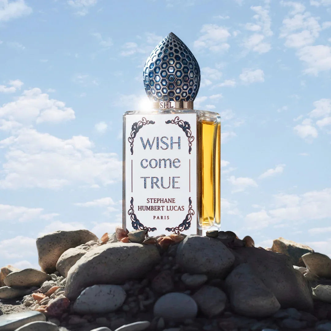 Flakon "Wish Come True" von Stéphane Humbert Lucas auf Steinen, mit einem dekorativen, blauen Verschluss.