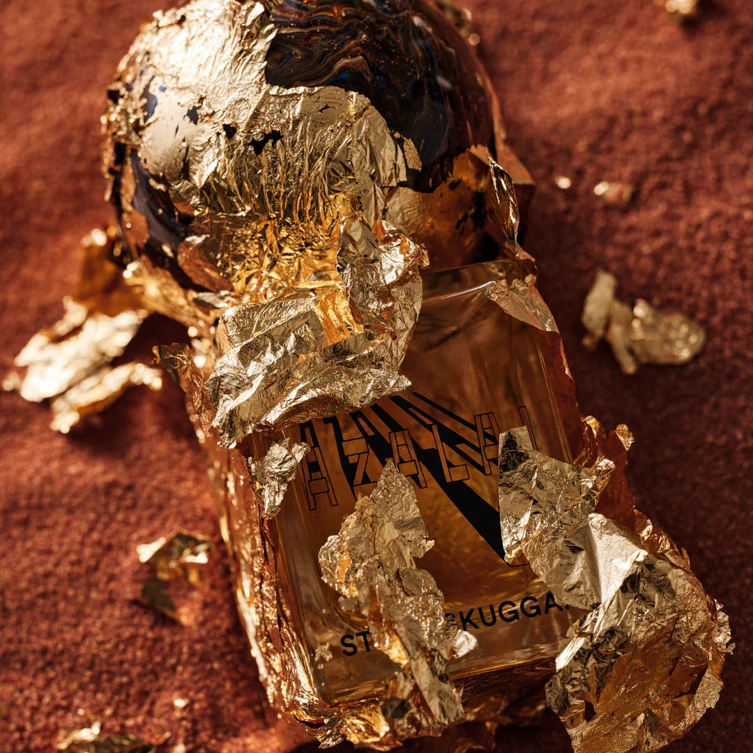 Parfümflasche "Azalai" von Stora Skuggan, umhüllt von goldfarbenem Blattmetall, mit schwarzem Logo auf dem Glas.